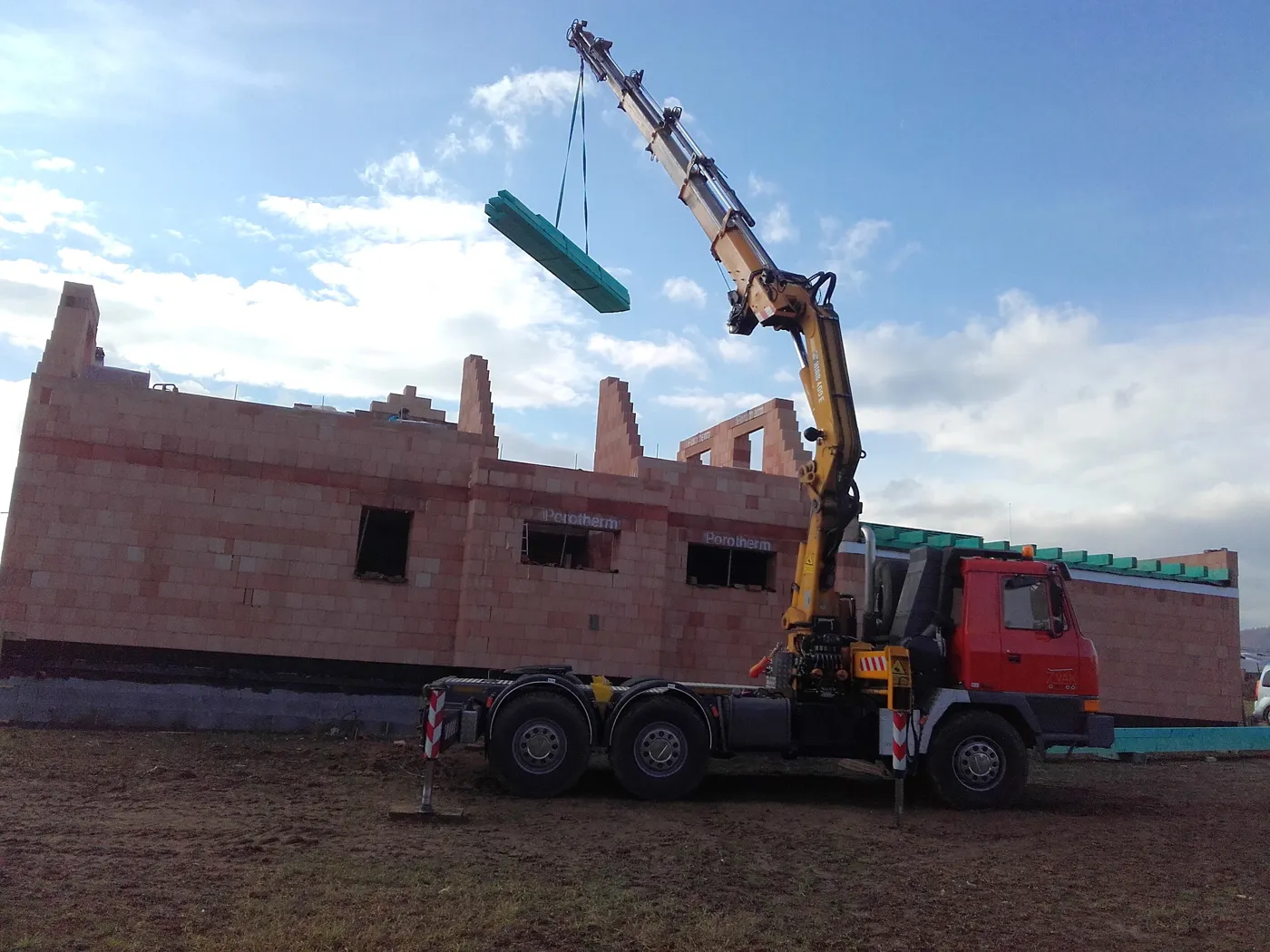 Hydraulická ruka skládá stavební materiál na stavbě