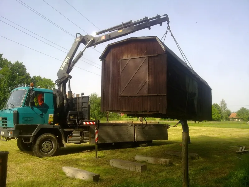 Tyrkysová TATRA 815 s hydraulickou rukou HIAB skládá dřevěnou stavbu